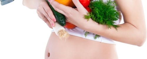 Healthy eating - Portrait of a pregnant woman with vegetables while isolated on white background